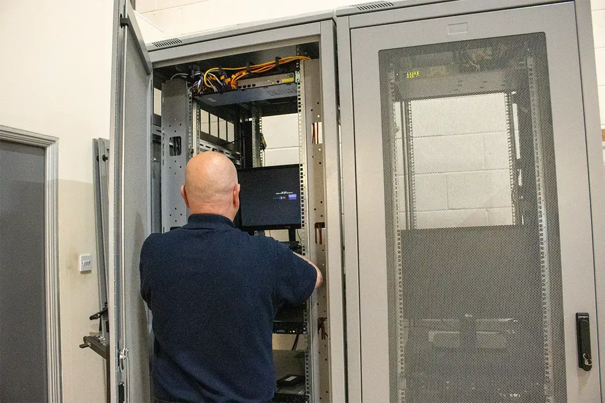 MT Service employee Installing IT inferstructure using a computer in a server cage business continuity and disaster recovery